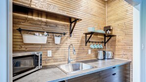 A modern kitchen with wooden paneling, a stainless steel sink, a built-in oven, and a dish rack.