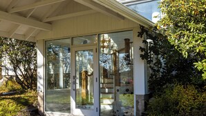A covered porch with glass doors, a stone staircase, and a view of a garden.