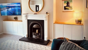 A living room with a fireplace, a television, and a framed picture on the wall. - Quiet 2BR Home with Garden, Sleeps 5 (Londonderry)