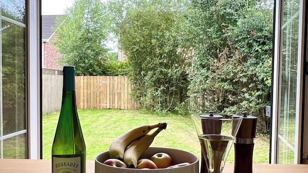 A table with a bottle, a bowl of fruit, and a glass. - Quiet 2BR Home with Garden, Sleeps 5 (Londonderry)