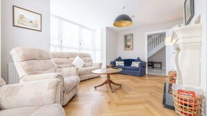 Ein Wohnzimmer mit einer Couch, Sesseln, einem Couchtisch und einem Kamin.