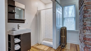 A modern bathroom with a wooden vanity, a white shower enclosure, and a radiator.