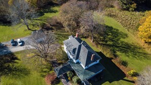 A large house with a steep roof, surrounded by a well-maintained lawn and trees.
