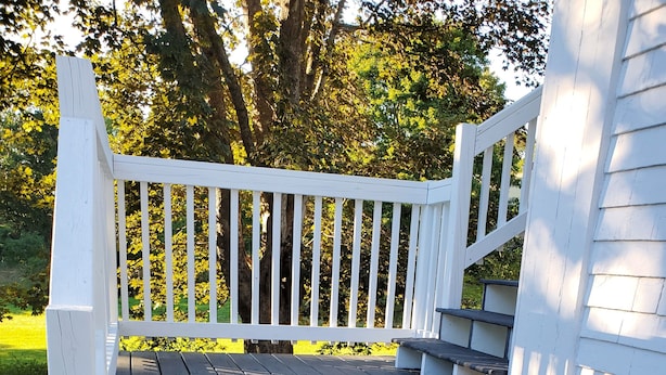 A wooden deck with white railings and steps leading to a house.