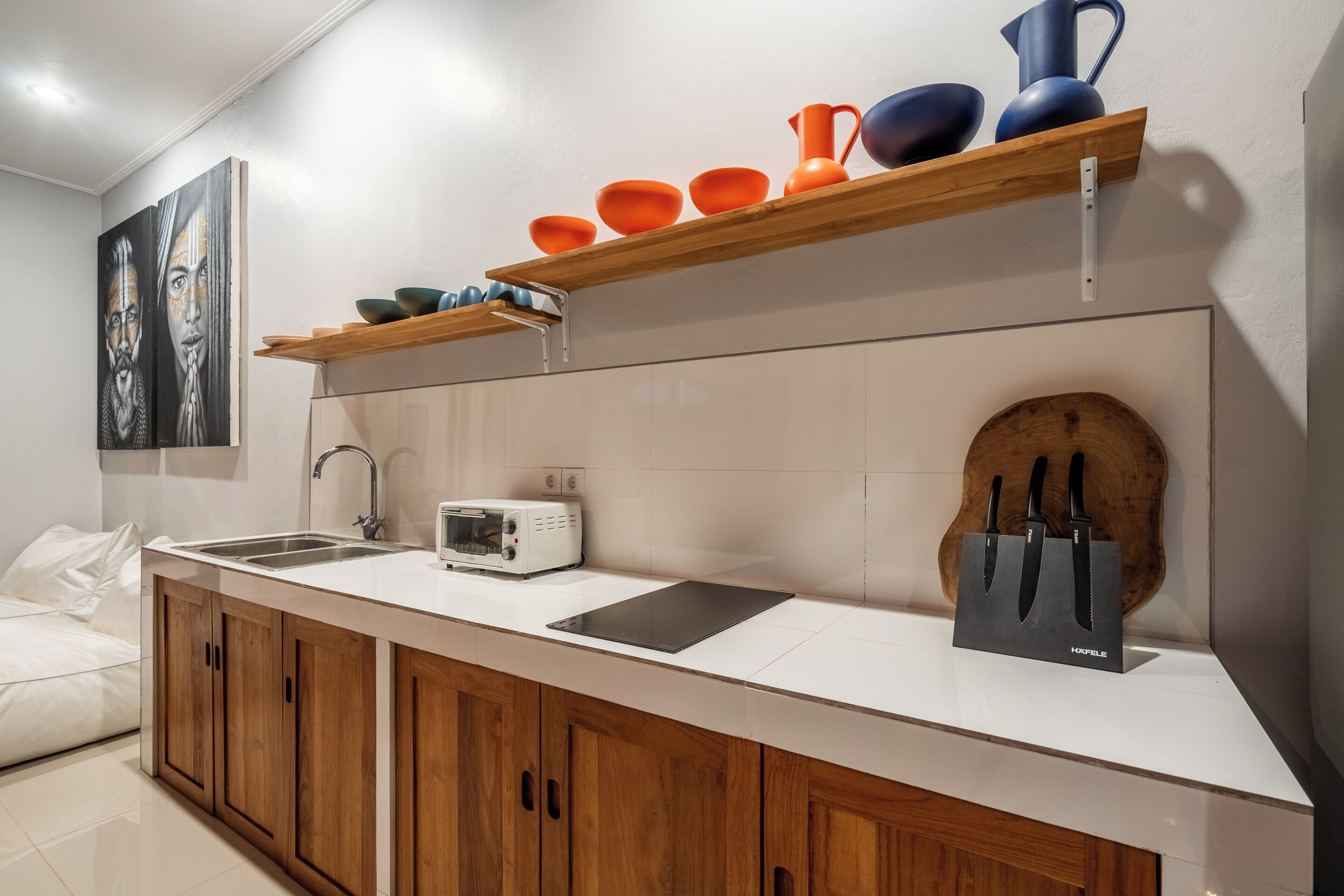 A modern kitchen with a white countertop, wooden cabinets, a toaster, and a knife block.