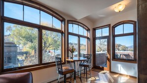 A room with large arched windows, a wooden floor, and a table with chairs.