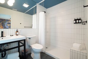 A bathroom with a white sink, toilet, and shower area.