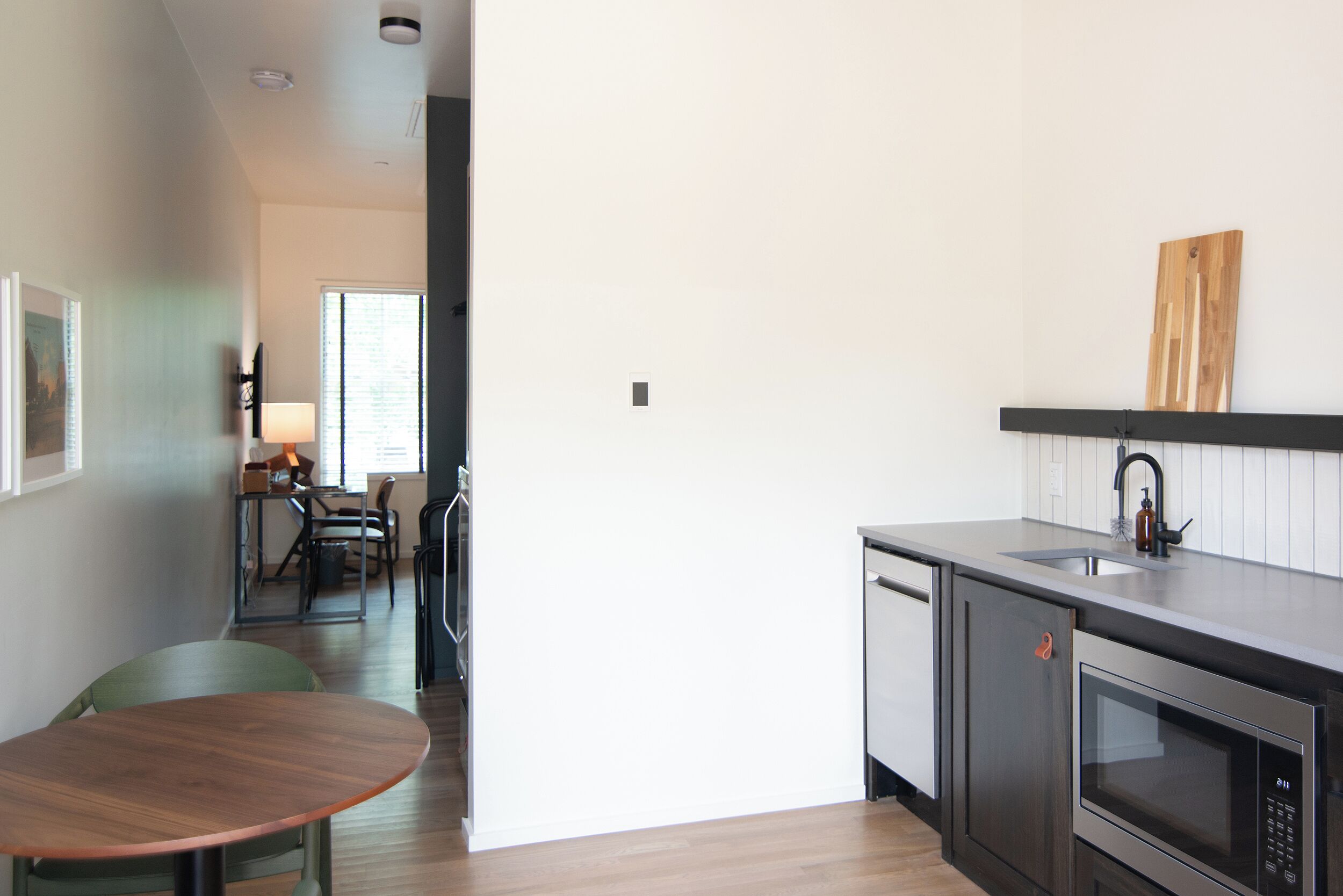 A modern kitchen with a built-in microwave, a sink, and a dining area with a table and chairs.