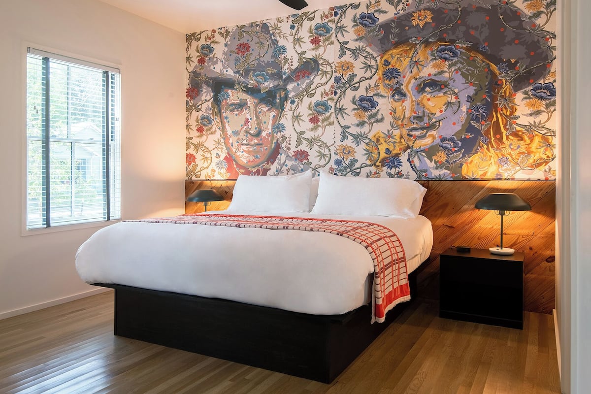 Un dormitorio con una cama grande, dos mesitas de noche y una pared con un mural floral.