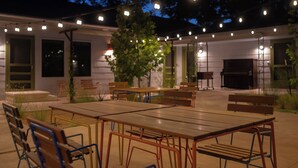 An outdoor patio area with tables and benches, string lights, and a tree. - Talbot Commons Hotel (Taylor)