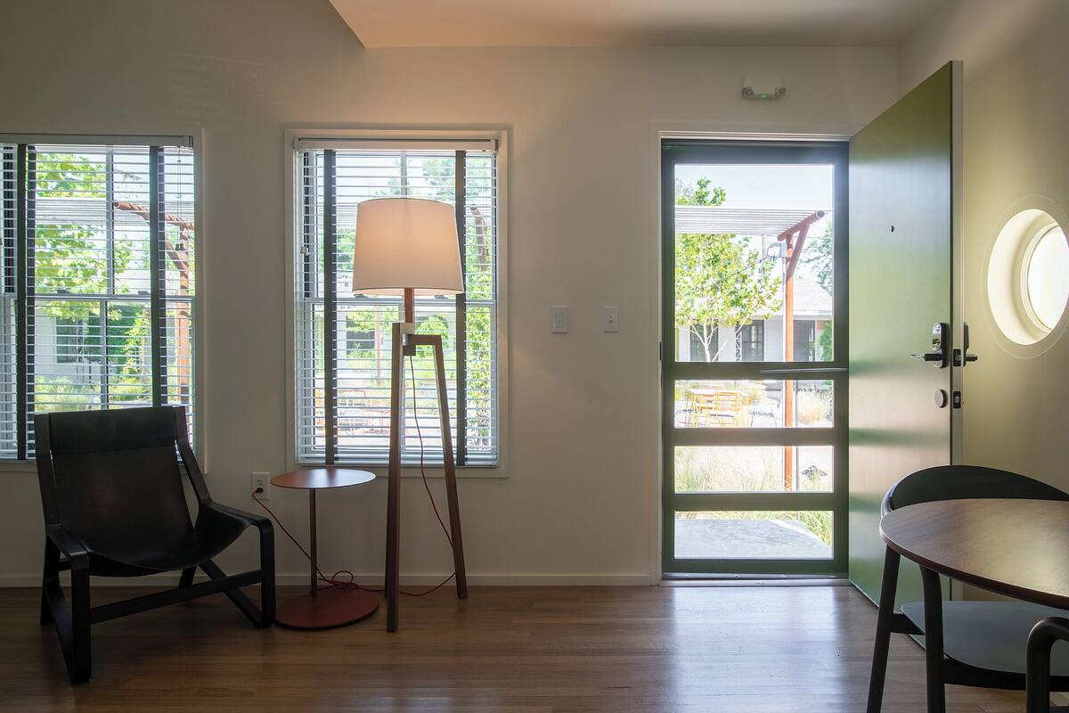 Una habitación con dos sillas, una lámpara y una puerta que da al exterior.