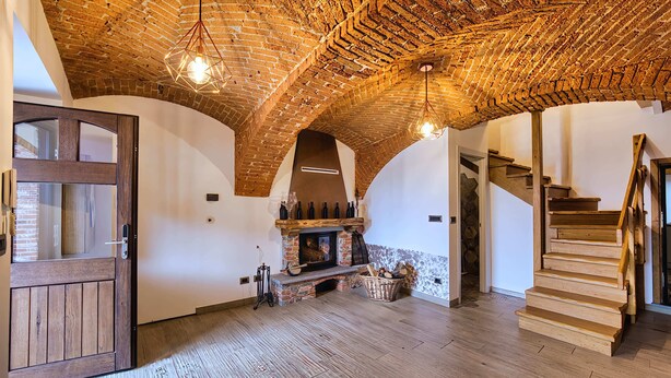 A spacious room with a brick ceiling, a fireplace, and a wooden staircase. - La Cantina Rent Rooms (Santa Maria-San Grato)