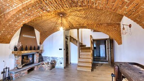 A spacious room with a brick ceiling, a fireplace, wooden flooring, and a staircase leading to another level. - La Cantina Rent Rooms (Santa Maria-San Grato)