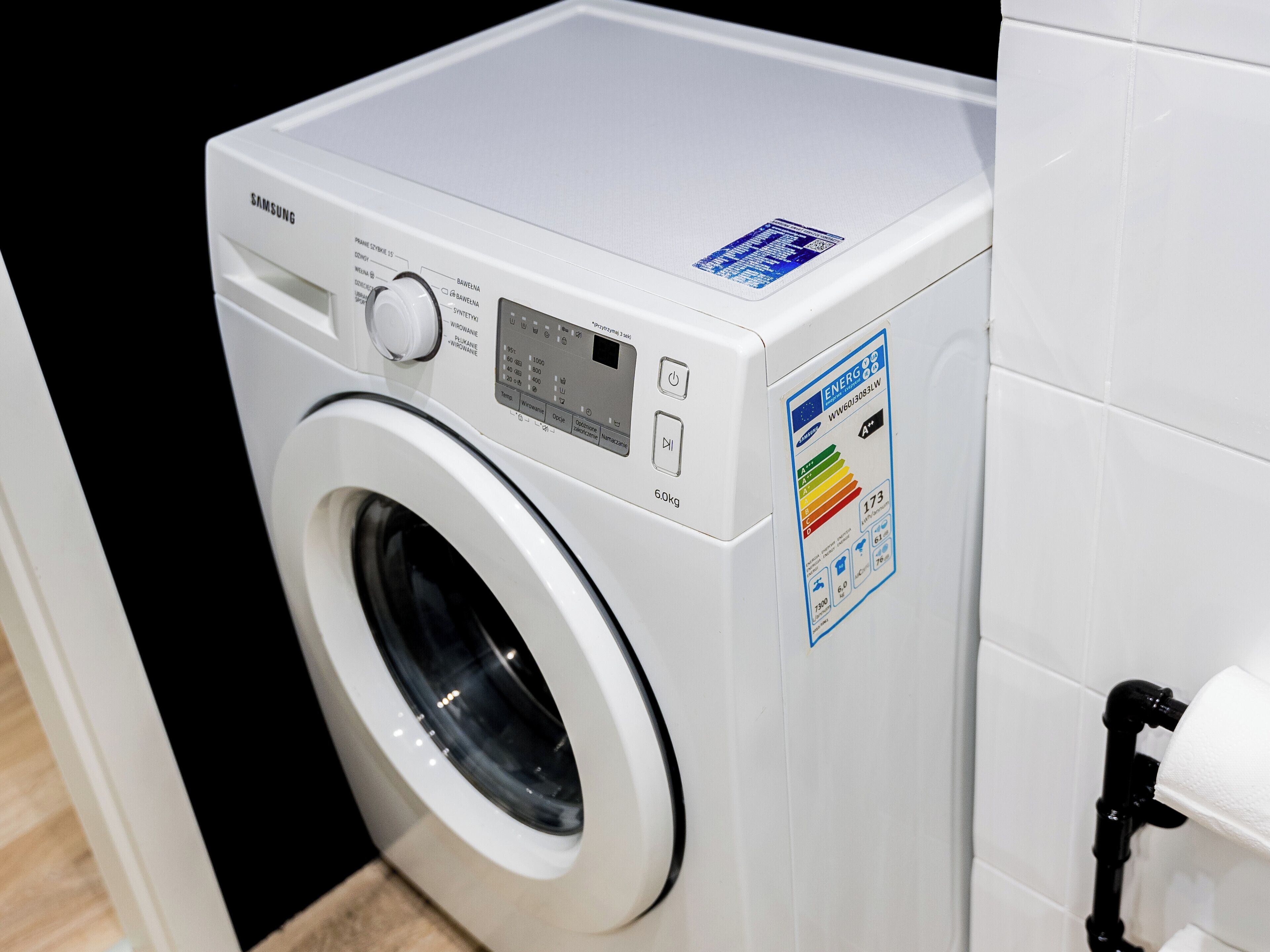 A front view of a Samsung front-loading washing machine with a digital control panel, a power cord, and an ENERGY label.