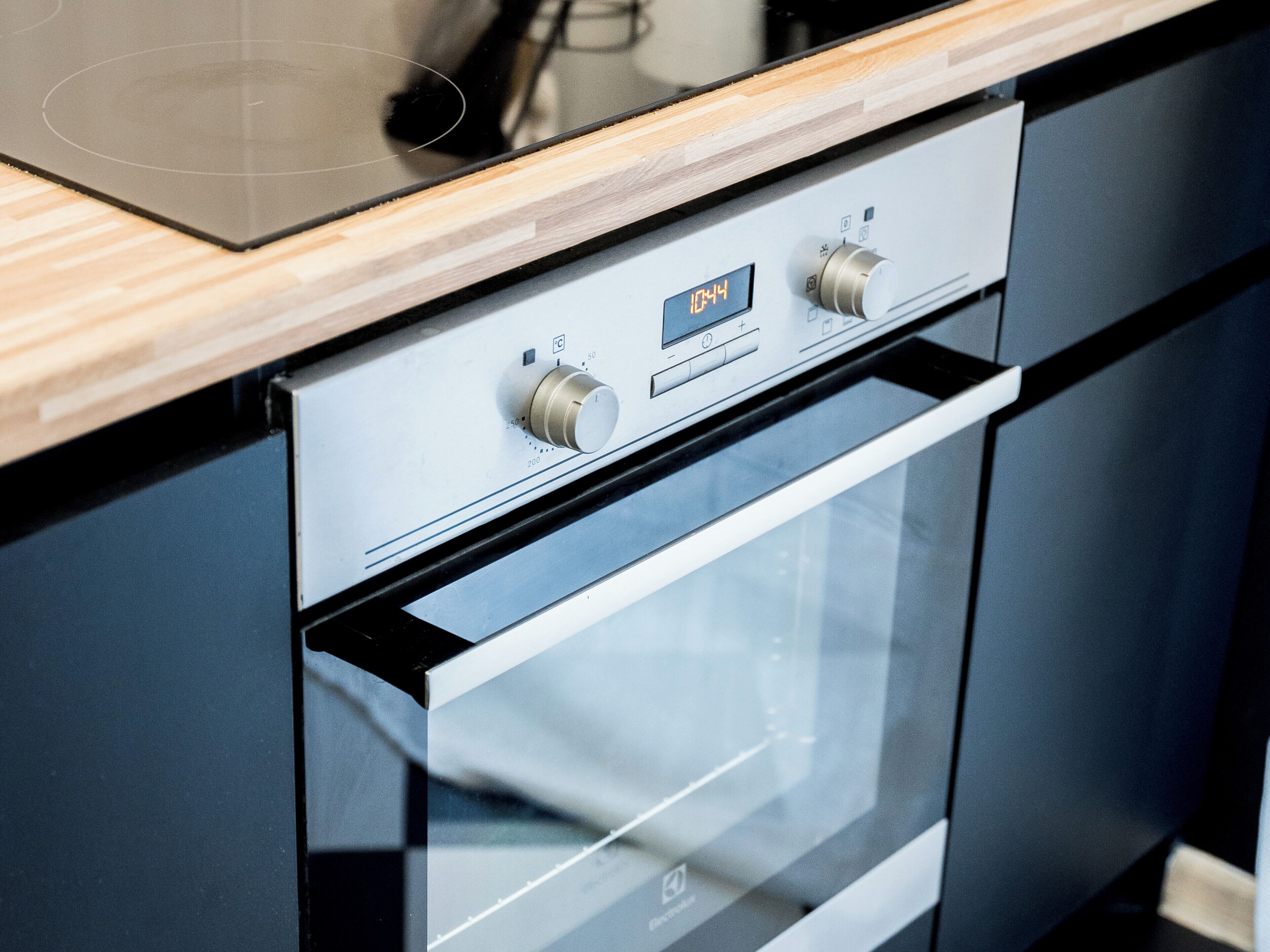 Una cucina moderna con forno integrato e orologio digitale che segna le 10:44.