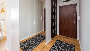 Un pasillo moderno con un separador de vidrio, una puerta de madera y un rug con diseño.