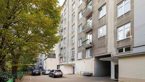 A multi-story residential building with balconies, a paved driveway, and parked cars. - Urban Heart Deluxe Studio #2 (Warszawa)