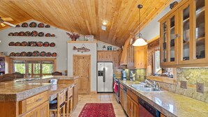 A spacious kitchen with wooden cabinets, a granite countertop, and a red rug.