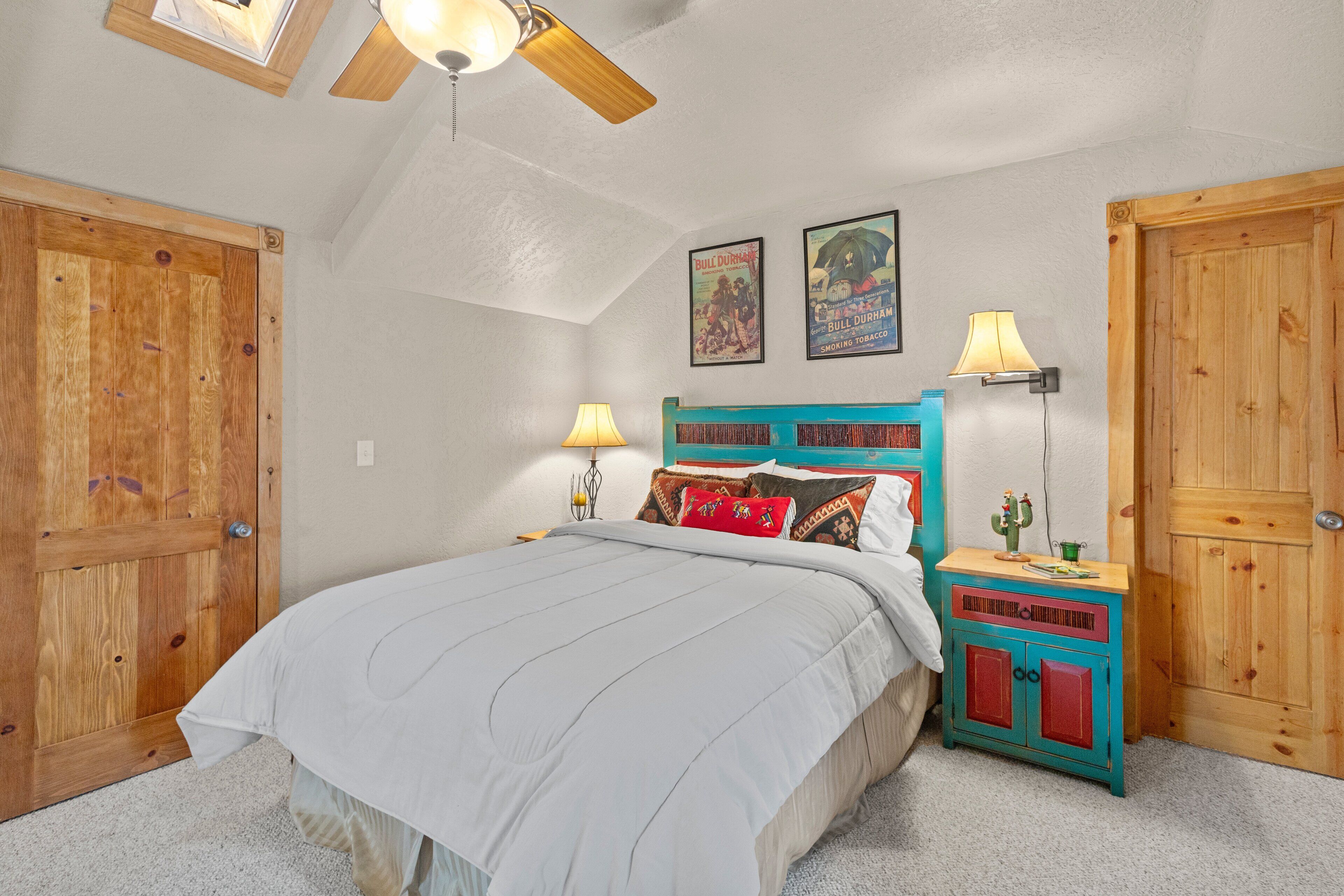 A bedroom with a bed, wooden wardrobe, nightstands, and a ceiling fan.