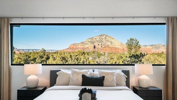 Een slaapkamer met een groot raam dat uitzicht biedt op een berg en bos.
