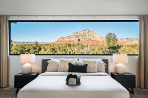 Une chambre avec une grande fenêtre donnant sur un paysage de montagne et de forêt.