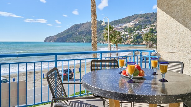 Un balcon avec une table, des chaises et une vue sur la plage et l’océan.