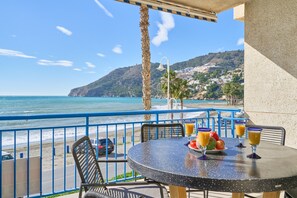 A balcony with a table, chairs, and a view of the beach and ocean. - Apartment 'Beachfront Los Novos La Herradura' with Sea View, Wi-Fi and Air Conditioning (La Herradura)