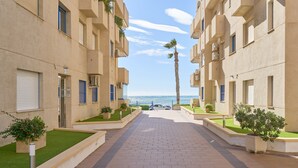 Un chemin menant à un bâtiment doté de balcons, avec un palmier et une vue sur la mer.
