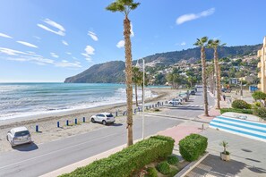 A coastal road with palm trees, a beach, and a hilly town in the background. - Apartment 'Beachfront Los Novos La Herradura' with Sea View, Wi-Fi and Air Conditioning (La Herradura)
