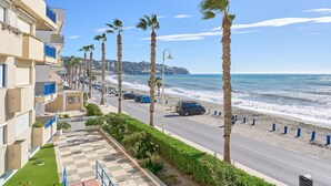 Une route côtière bordée de palmiers, une plage et un immeuble doté de balcons.