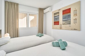A hotel room with two beds, beige curtains, a window, and a painting on the wall. - Apartment 'Beachfront Los Novos La Herradura' with Sea View, Wi-Fi and Air Conditioning (La Herradura)