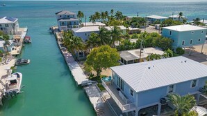 Una zona residencial costera con casas a lo largo de un canal estrecho, muelles y barcos.