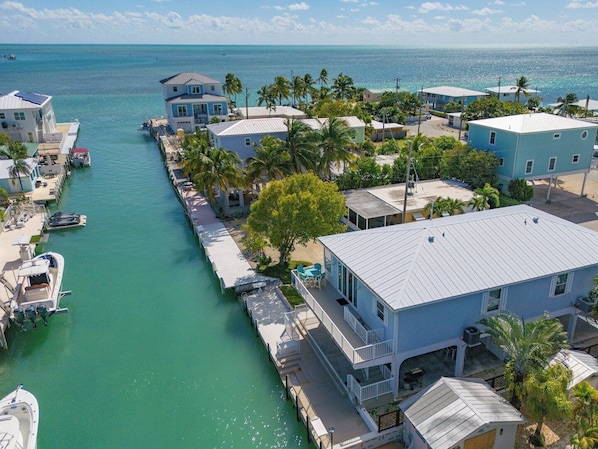 A coastal residential area with houses along a narrow waterway, docks, and boats.