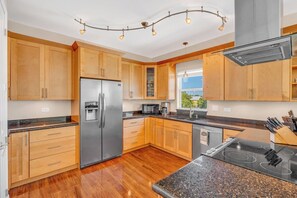 Una cocina moderna con armarios de madera, electrodomésticos de acero inoxidable, encimeras de granito y horno empotrado.