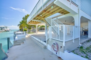 A waterfront property with a covered outdoor area, a staircase leading to a balcony, and a view of the water.