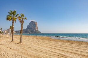 A sandy beach with palm trees and a rocky cliff in the background. - Apartment 'Casa Jaiwen' with Sea View, Wi-Fi and Air Conditioning (Calpe)