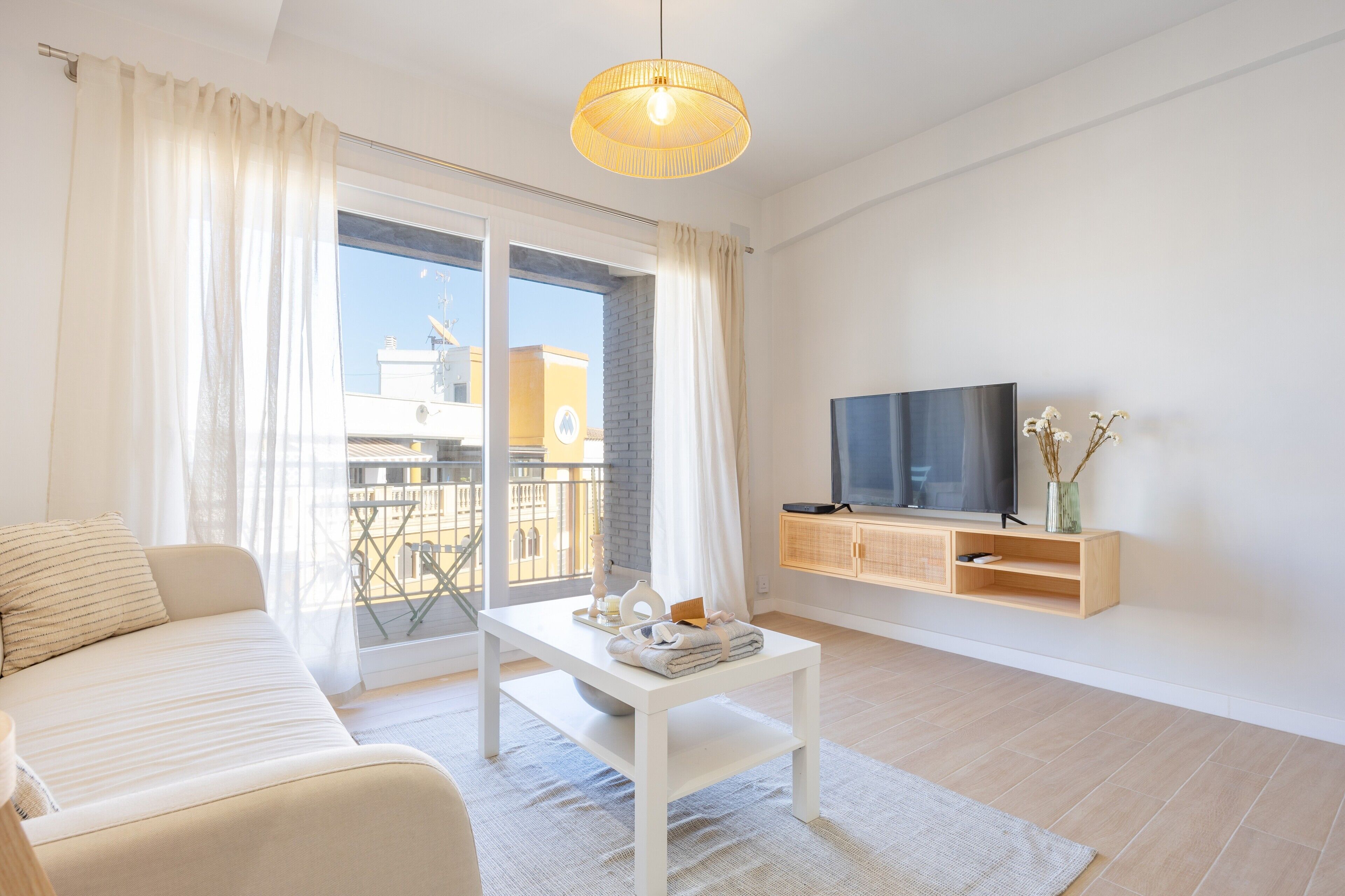 A modern living room with a sofa, coffee table, TV, and a balcony view.