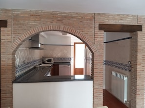 A kitchen with a brick archway, a microwave, a sink, and a dishwasher.