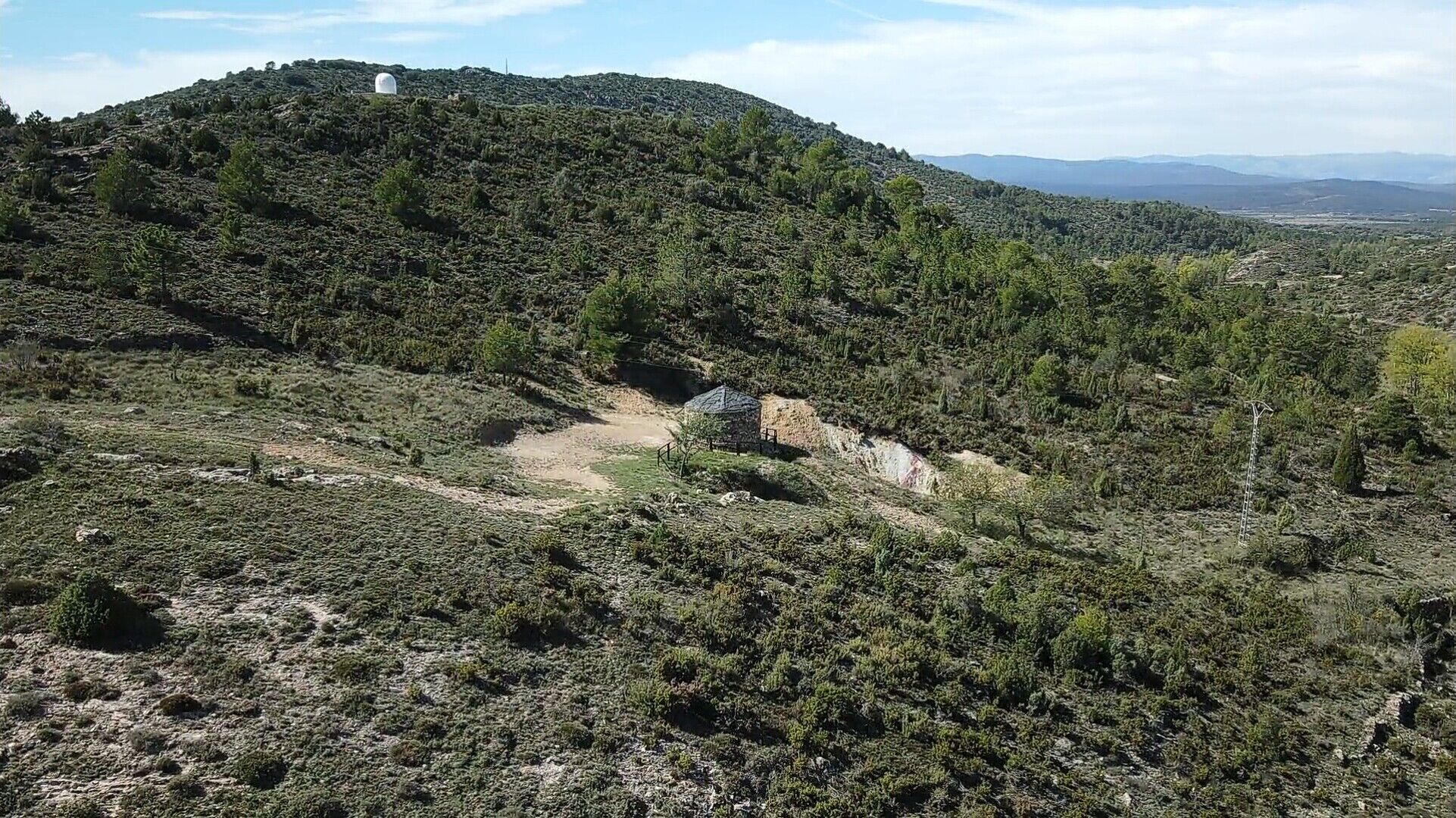 A mountainous landscape with a small structure on a hill.