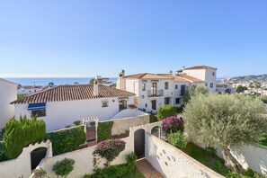 A coastal town with white buildings, terracotta roofs, and a clear view of the sea.
