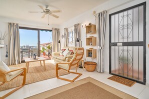 A spacious living room with a sofa, armchairs, a coffee table, and a ceiling fan.