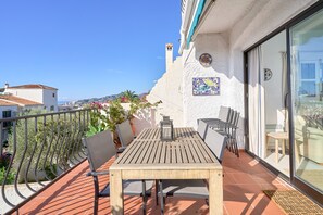 A terrace with a table and chairs, a potted plant, and a decorative tile.