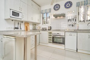 A modern kitchen with white cabinets, a microwave, a coffee maker, and a dishwasher.