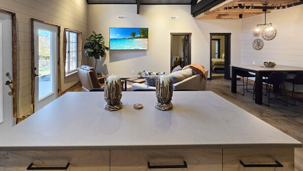 Una cocina amplia con una isla grande, armarios de madera y un comedor con mesa y sillas.