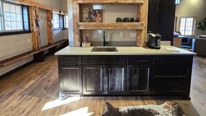 Una cocina con una isla central, armarios oscuros y una pared de acento de madera con la palabra "BOJI" sobre la isla.