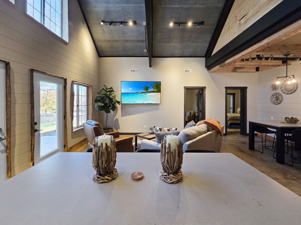 A spacious living area with a large table, a sofa, and a painting of a beach scene.