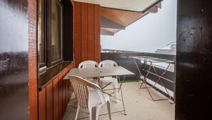 Un balcón con mesa y sillas, una ventana y vistas de un paisaje nevado.