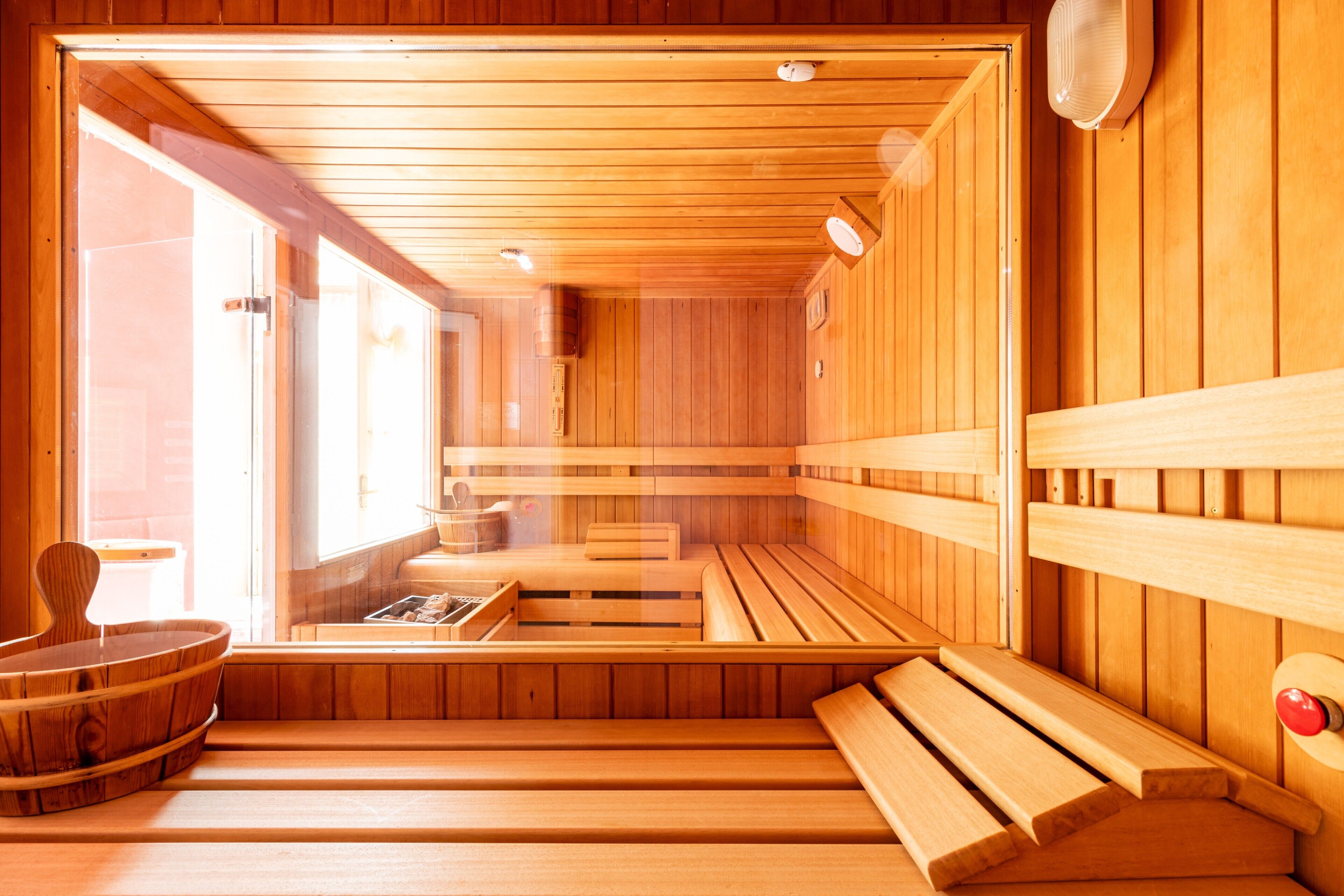 Eine Holzsauna mit Bänken und einer Sitzbank, Holzwänden und einem Fenster.