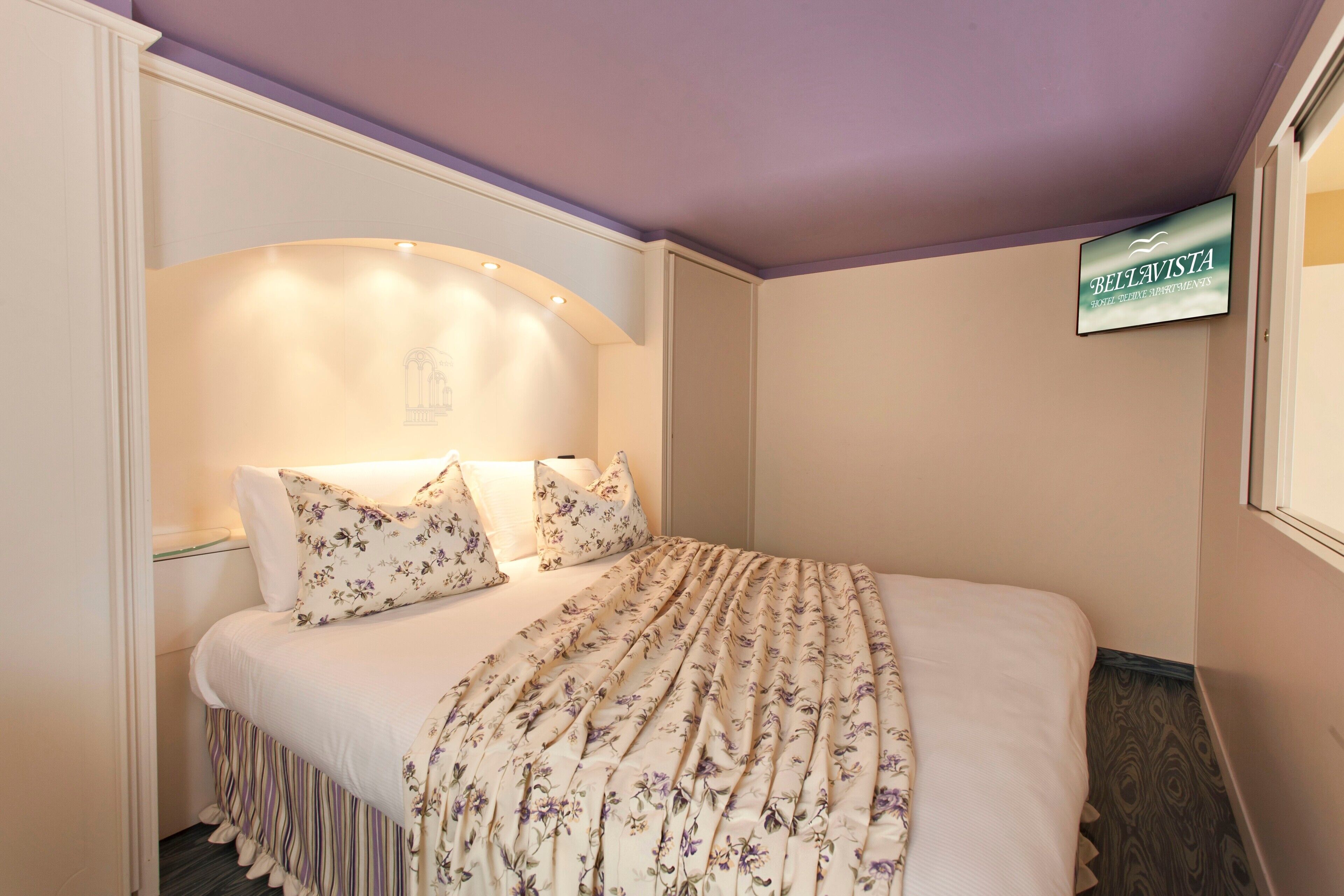 Ein Schlafzimmer mit einem Bett, Blumenbettwäsche, einem Kopfteil und einem Schild an der Wand.