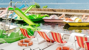 A row of colorful boats docked at a pier with mountains in the background.